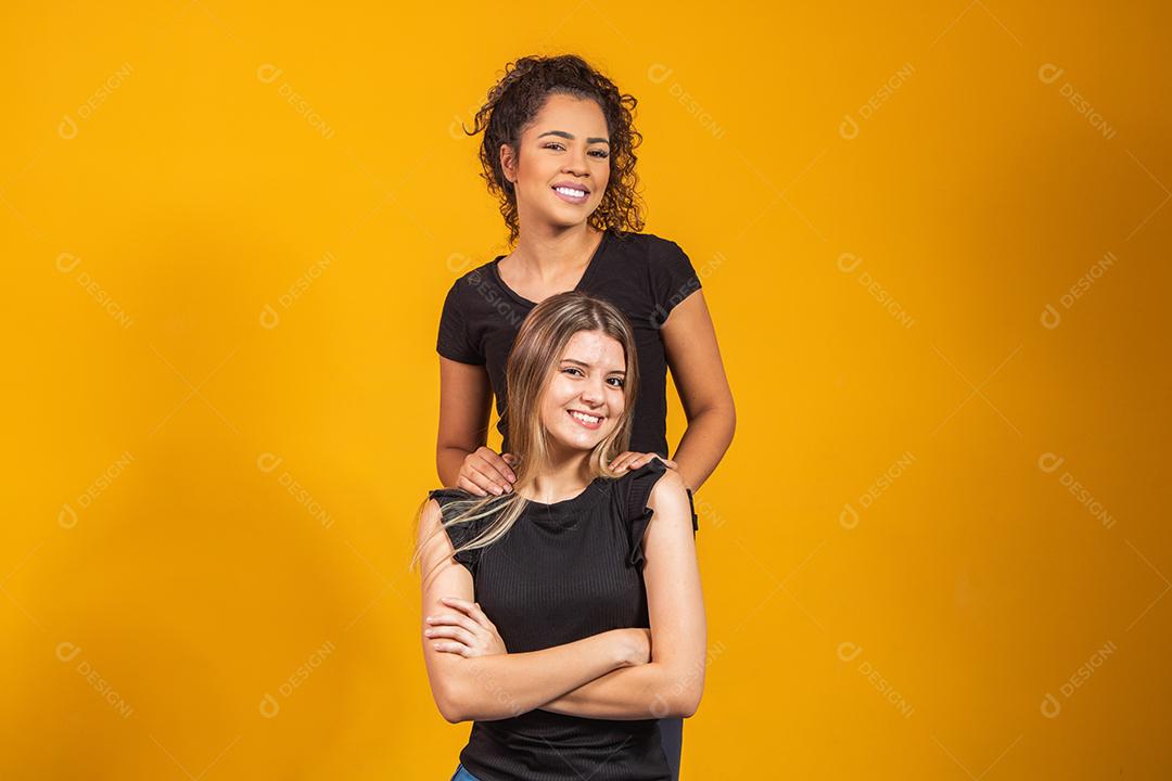 amigas de diferentes etnias abraçados em fundo amarelo