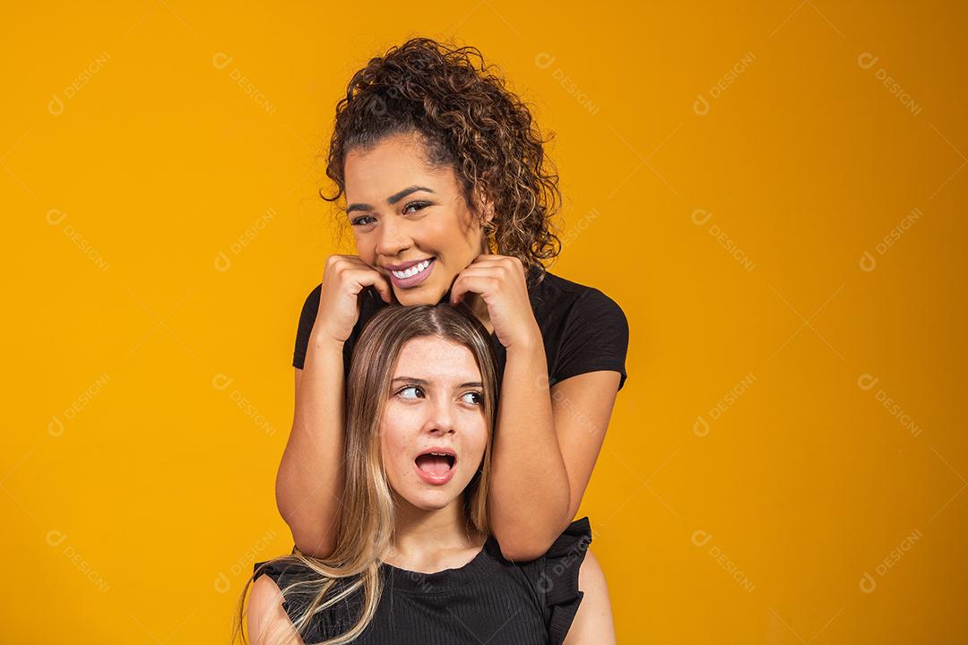 amigas de diferentes etnias abraçados em fundo amarelo