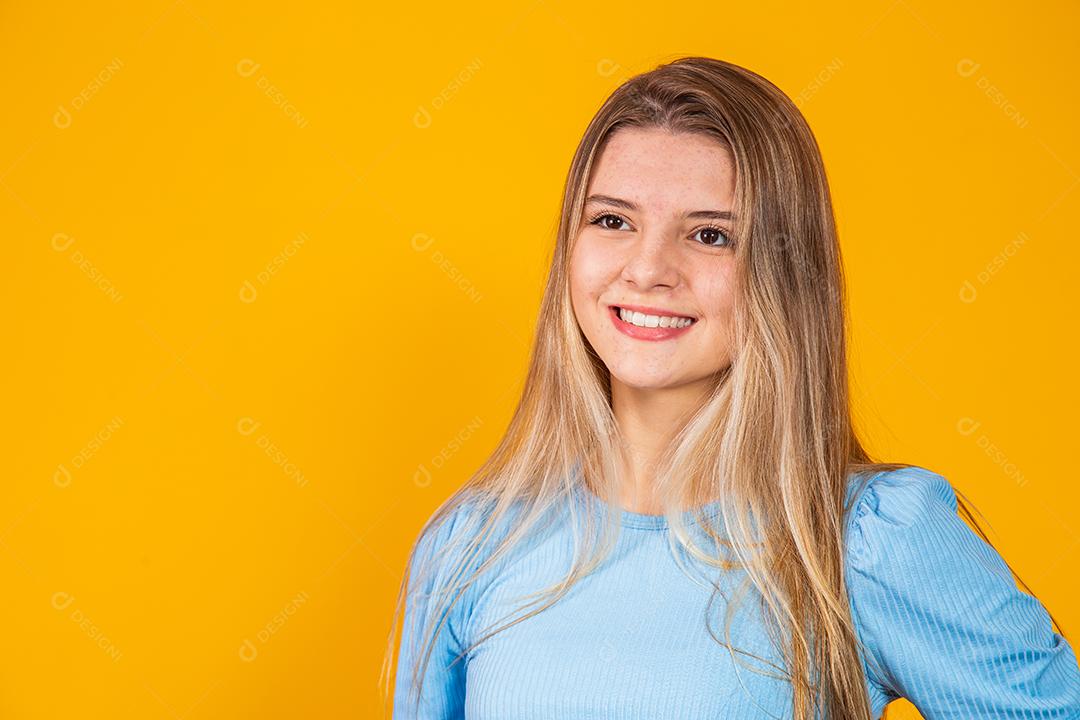 Jovem linda loira caucasiana feliz. Conceito de sucesso e realização. Alegre mulher loira bonita sobre fundo amarelo.