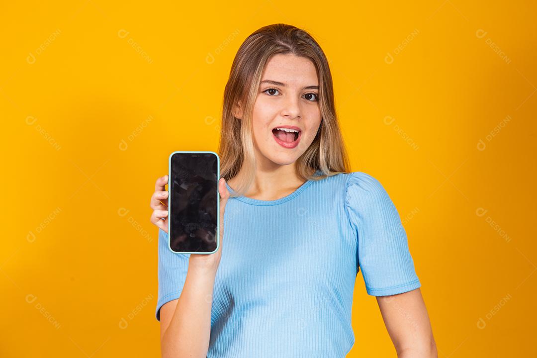 Jovem loira mostrando a tela do smartphone em branco enquanto olha