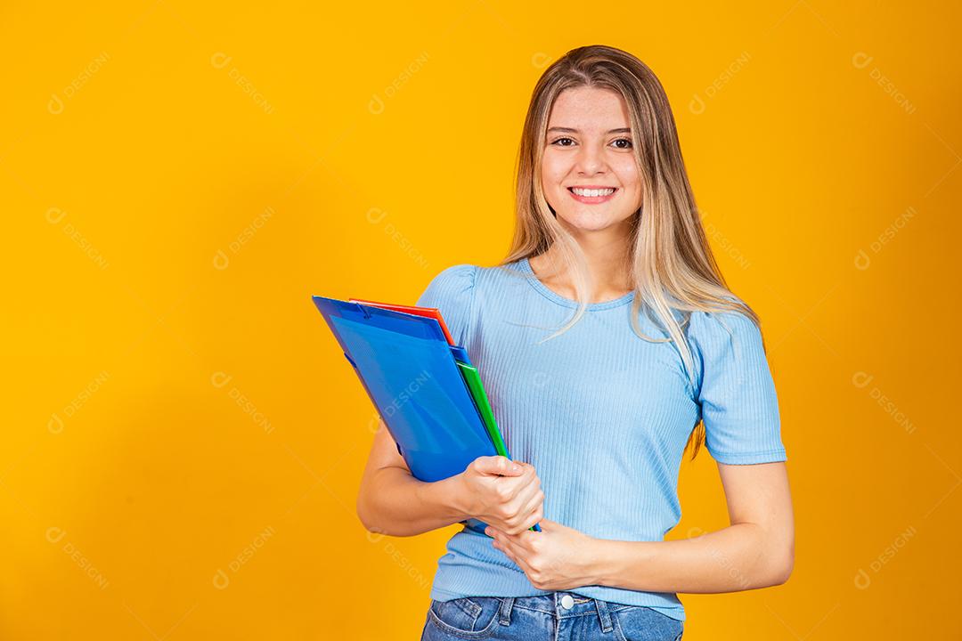 Aluna jovem Sorrindo com livros de volta para a escola sobre fundo amarelo