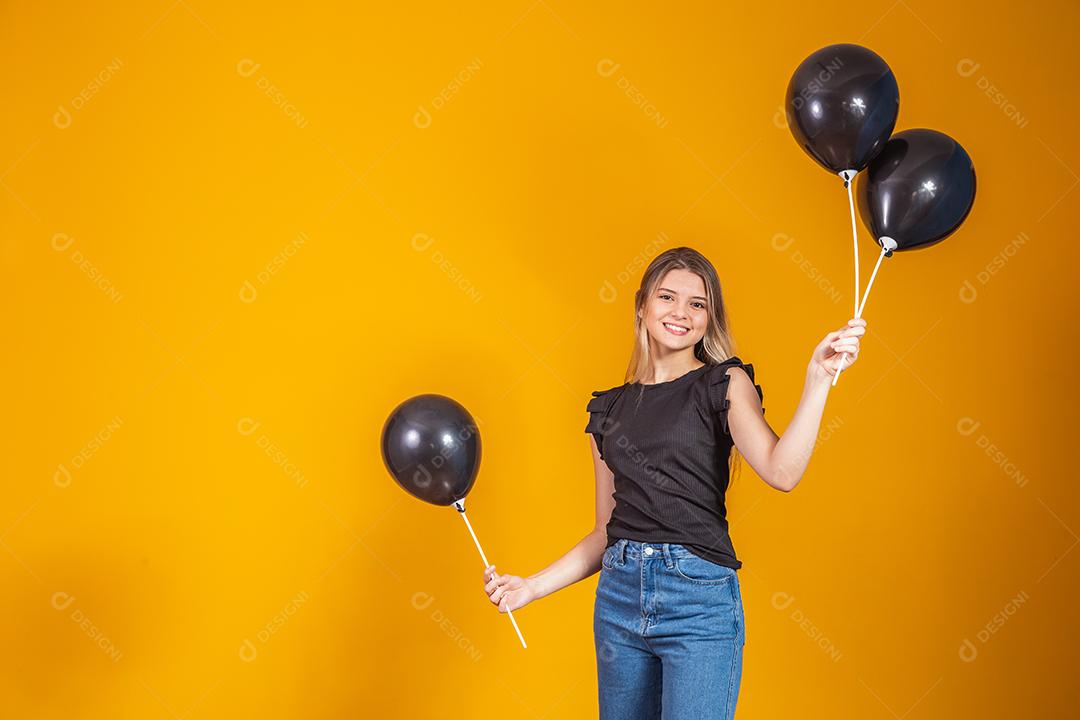 Sorrindo encantadora jovem segurando um celular e com Balões