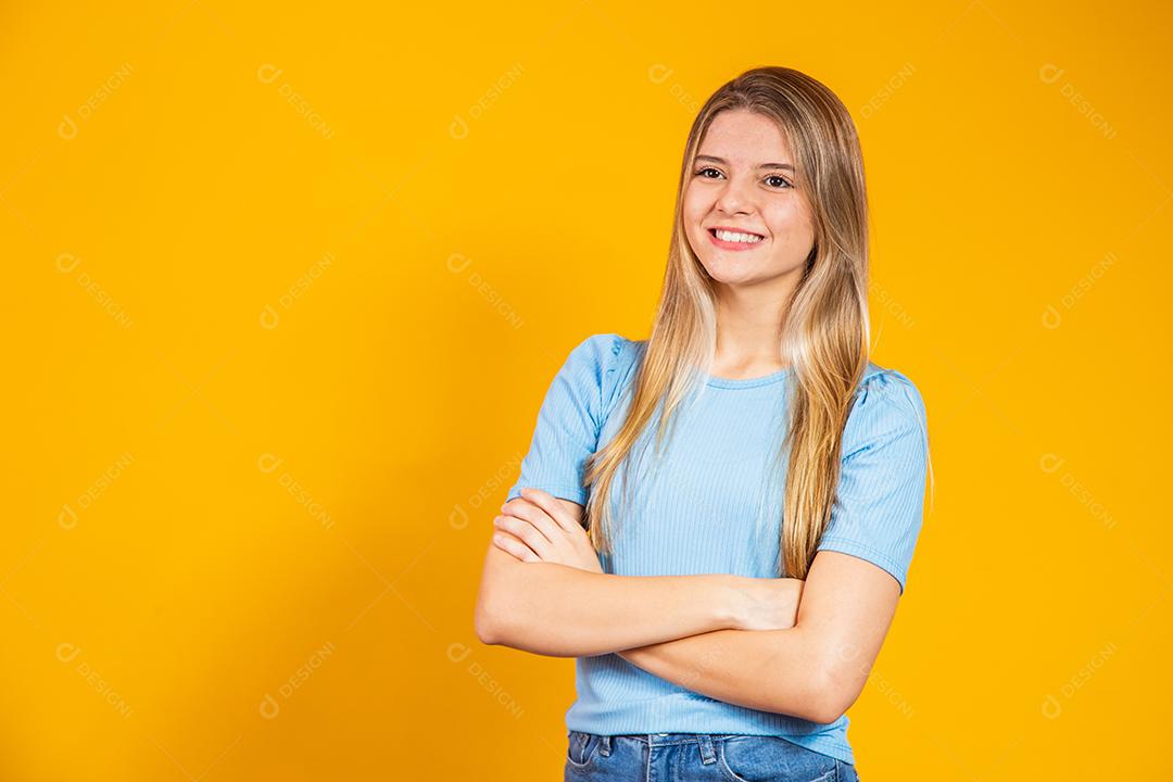Jovem mulher Sorrindo com braços cruzados sobre fundo amarelo isolado