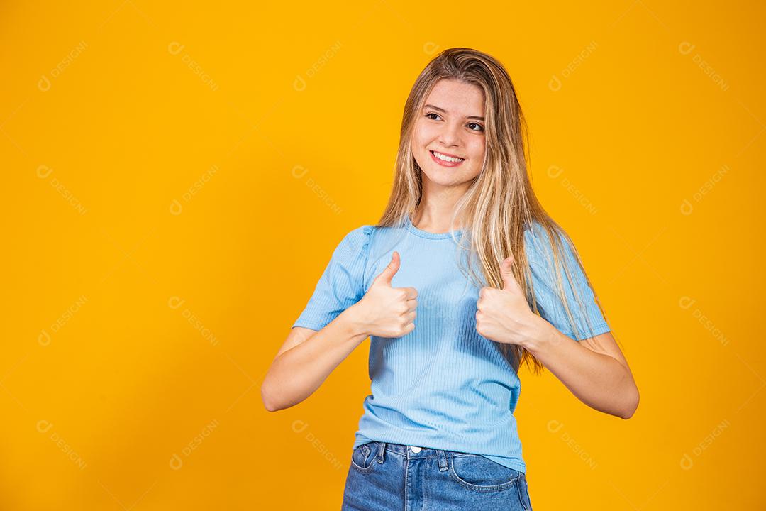 Jovem mulher Sorrindo e fazendo sinal de Beleza sobre fundo amarelo isolado