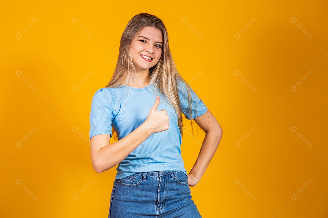 Jovem mulher Sorrindo e fazendo sinal de Beleza sobre fundo amarelo isolado