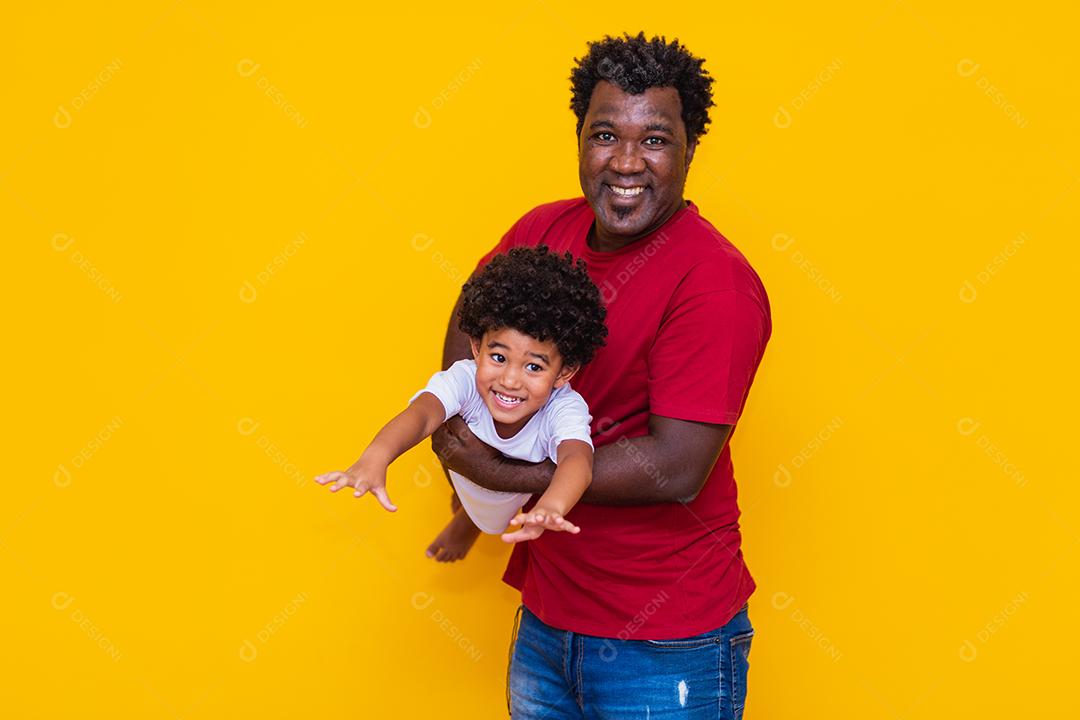 Pai e filho afro em fundo amarelo sorrindo e brincando