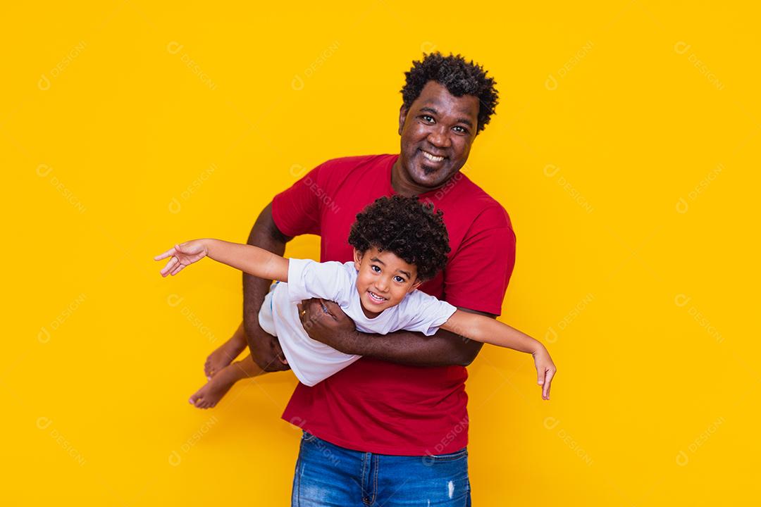 Pai e filho afro em fundo amarelo sorrindo e brincando