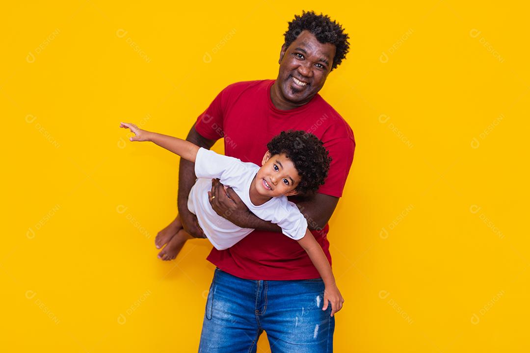 Pai e filho afro em fundo amarelo sorrindo e brincando