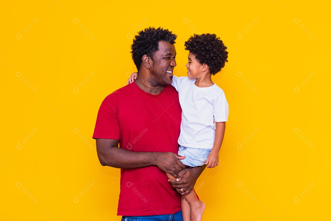 Pai e filho afro em fundo amarelo sorrindo
