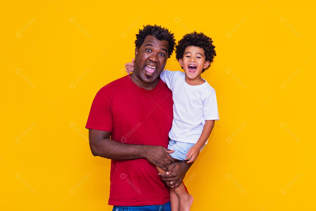 Pai e filho afro em fundo amarelo sorrindo