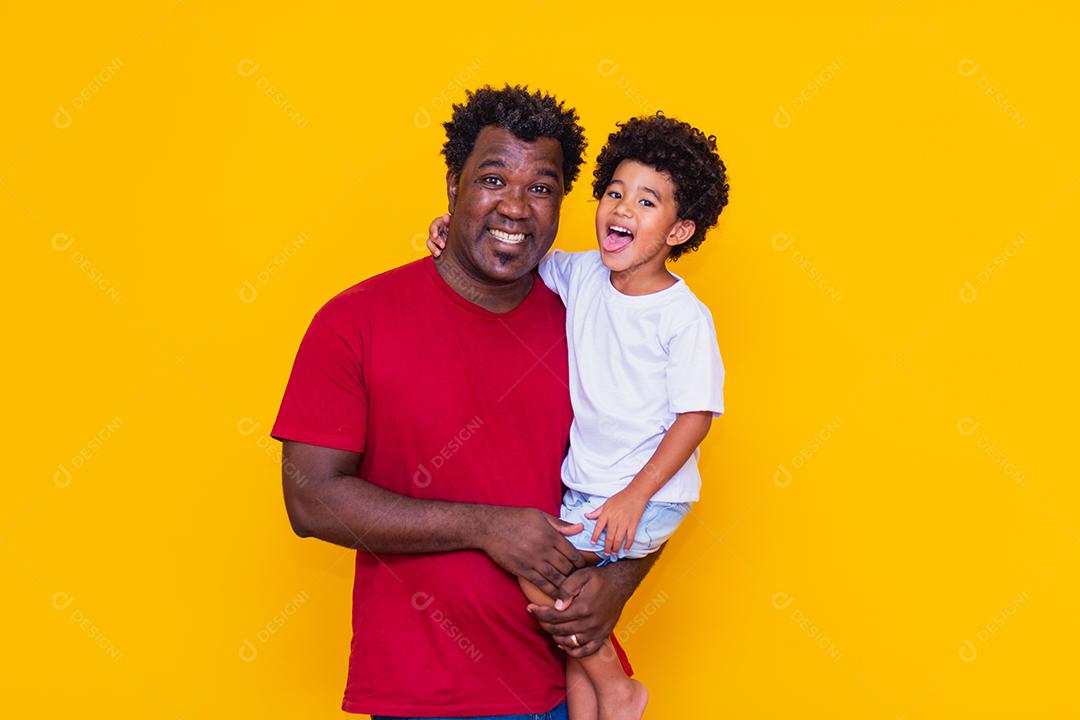 Pai e filho afro em fundo amarelo sorrindo