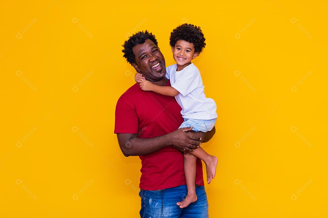 Pai e filho afro em fundo amarelo sorrindo e brincando