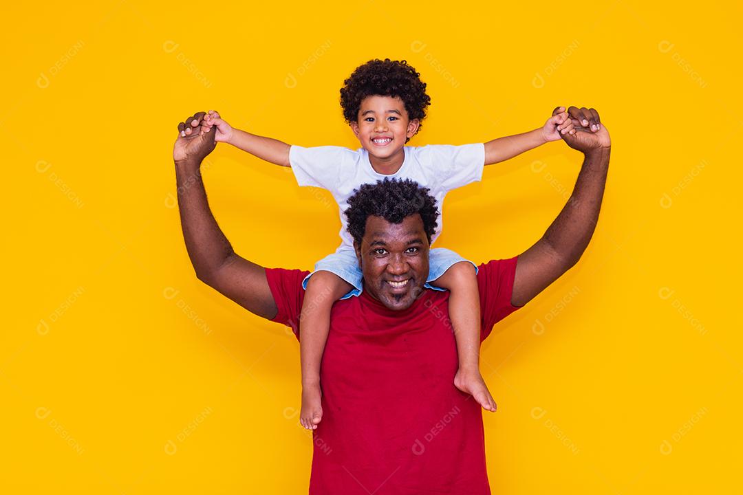 Pai e filho afro em fundo amarelo sorrindo e brincando