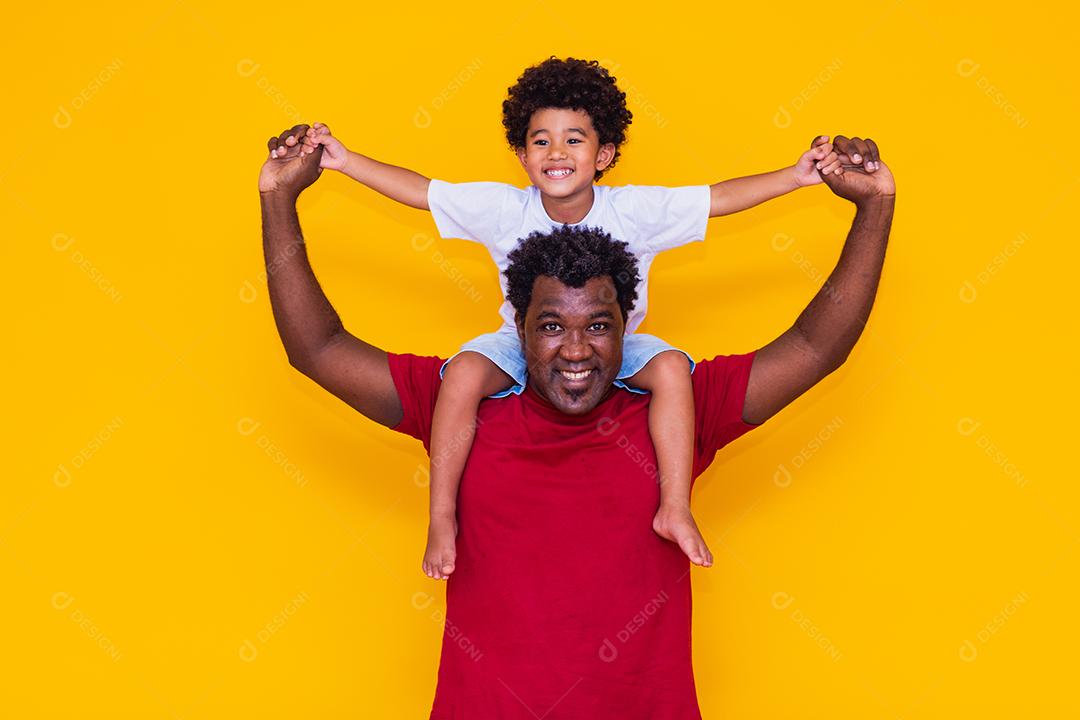 Pai e filho afro em fundo amarelo sorrindo e brincando