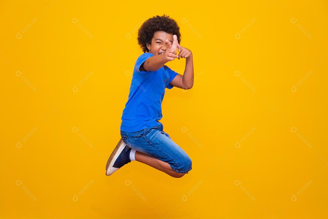 Afro boy jumping over yellow background
