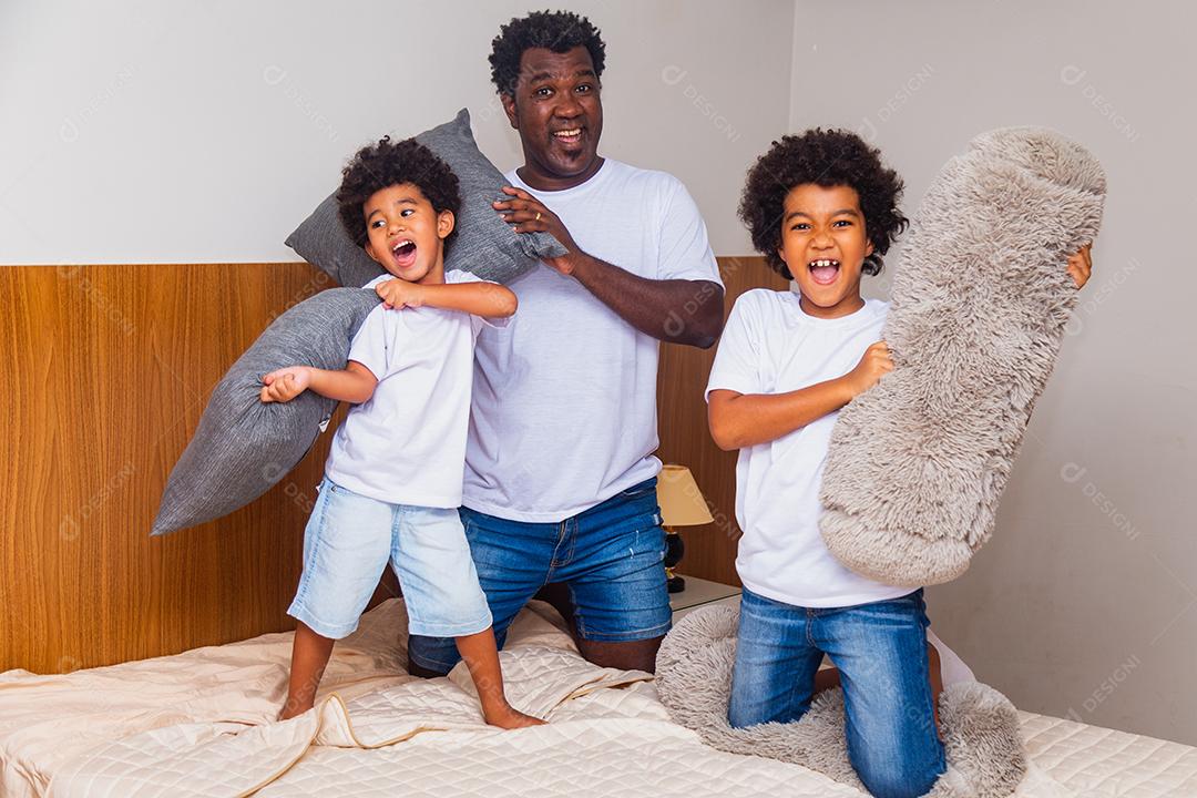 Pai e filhos Brincando na cama com travesseiros