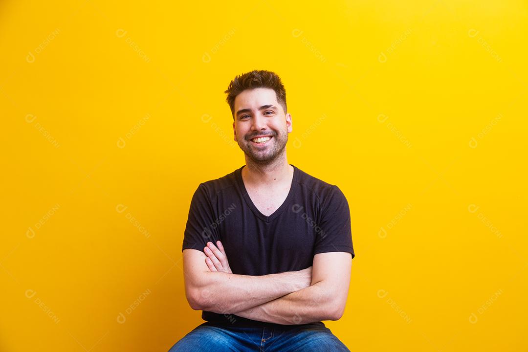 Homem bonito com os braços cruzados no fundo amarelo