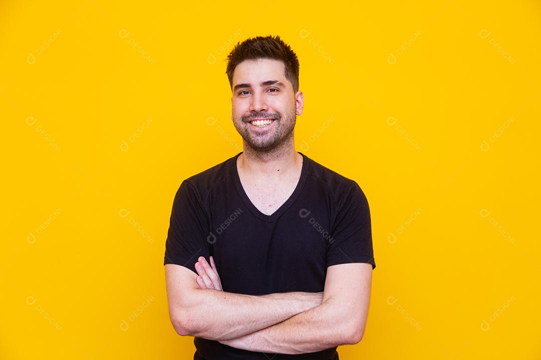 Homem bonito com os braços cruzados no fundo amarelo