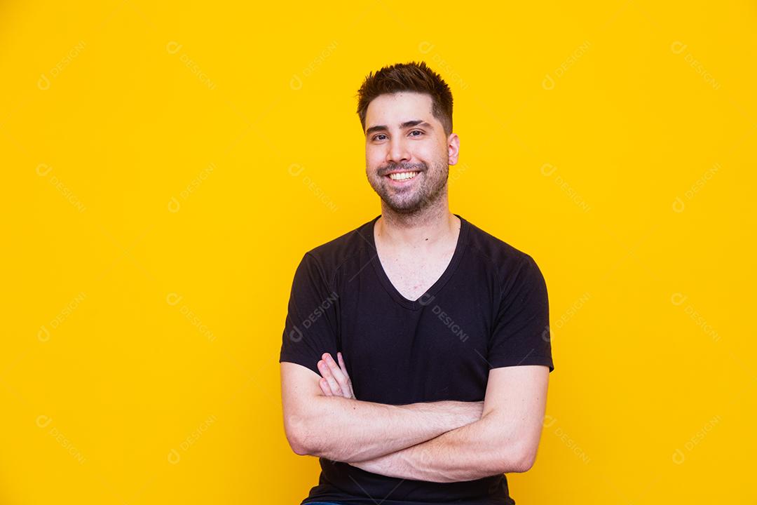 Homem bonito com os braços cruzados no fundo amarelo
