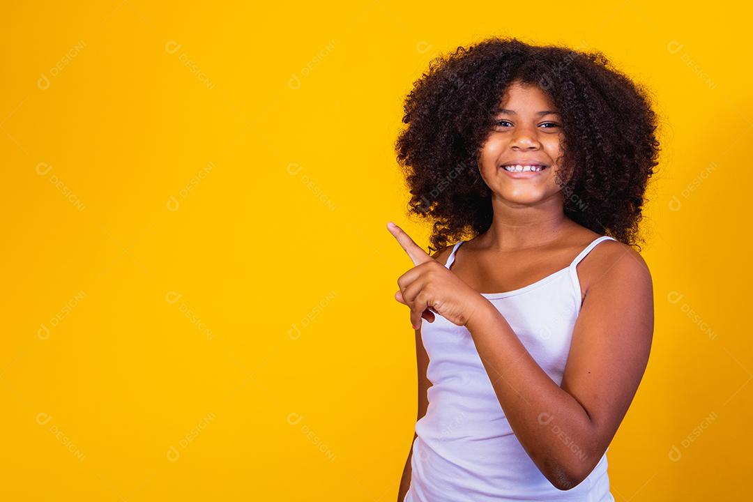beautiful afro child pointing to the side with copy space