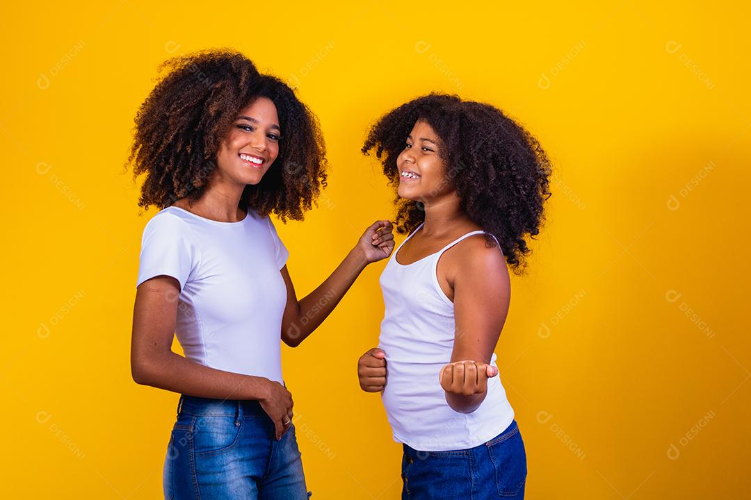 afro mãe e filha dançando em fundo amarelo