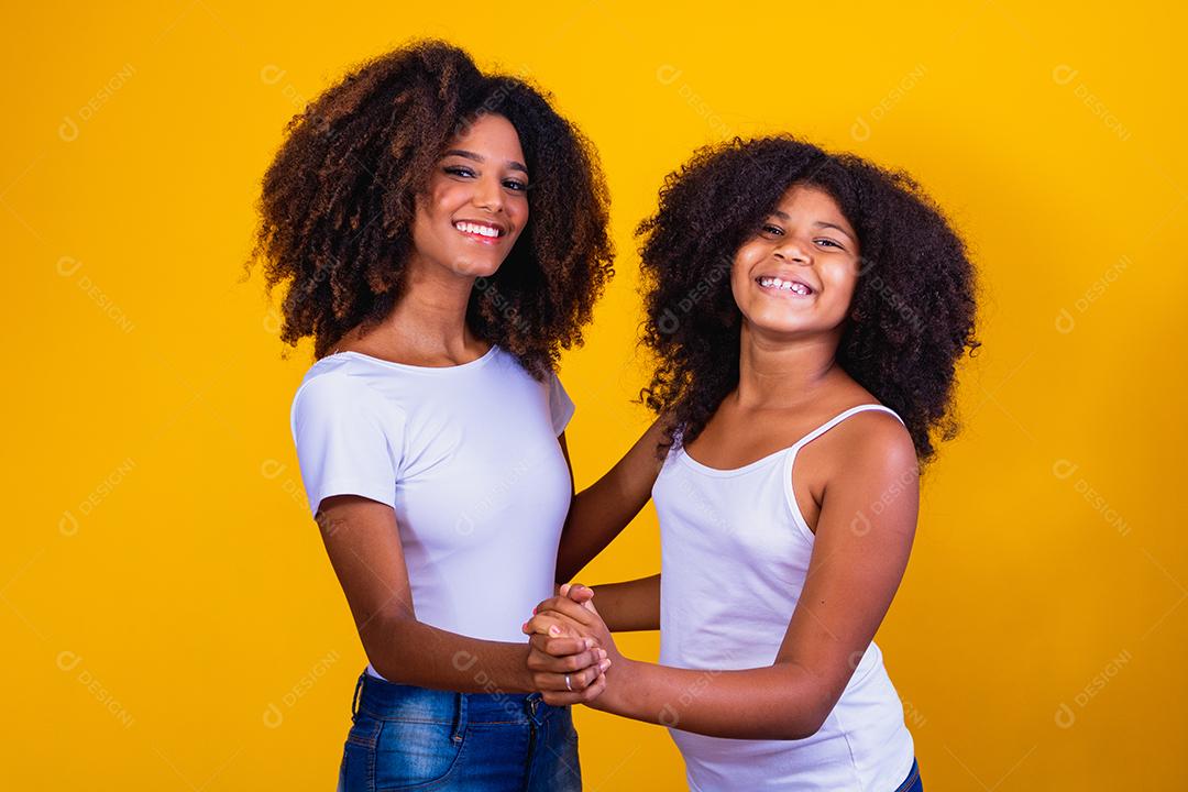 afro mãe e filha dançando em fundo amarelo