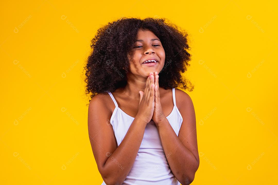 Linda criança afro-americana com as mãos juntas em gesto de oração expressando esperança e por favor conceito