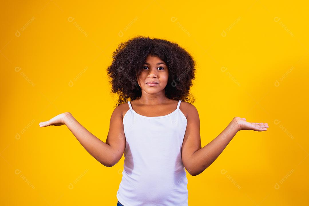 Menina bonita afro sobre expressão confusa e fundo isolado sem noção com braços e mãos levantadas. Conceito de dúvida.