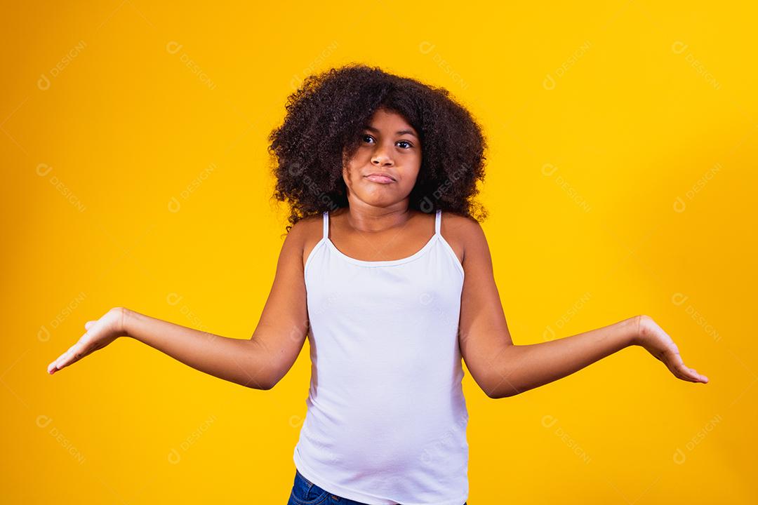 Menina bonita afro sobre expressão confusa e fundo isolado sem noção com braços e mãos levantadas. Conceito de dúvida.