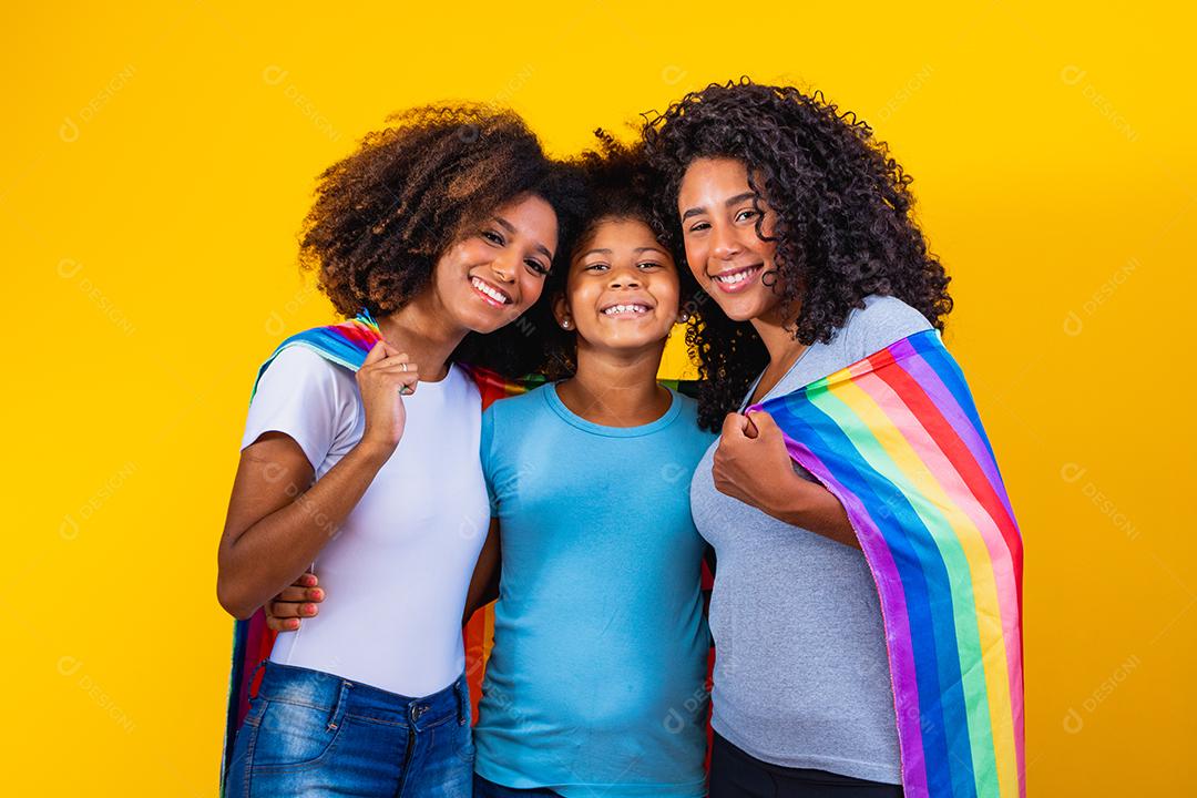 Feliz casal de lésbicas com criança em fundo amarelo. Casal junto com filha adotiva, conceito de adoção