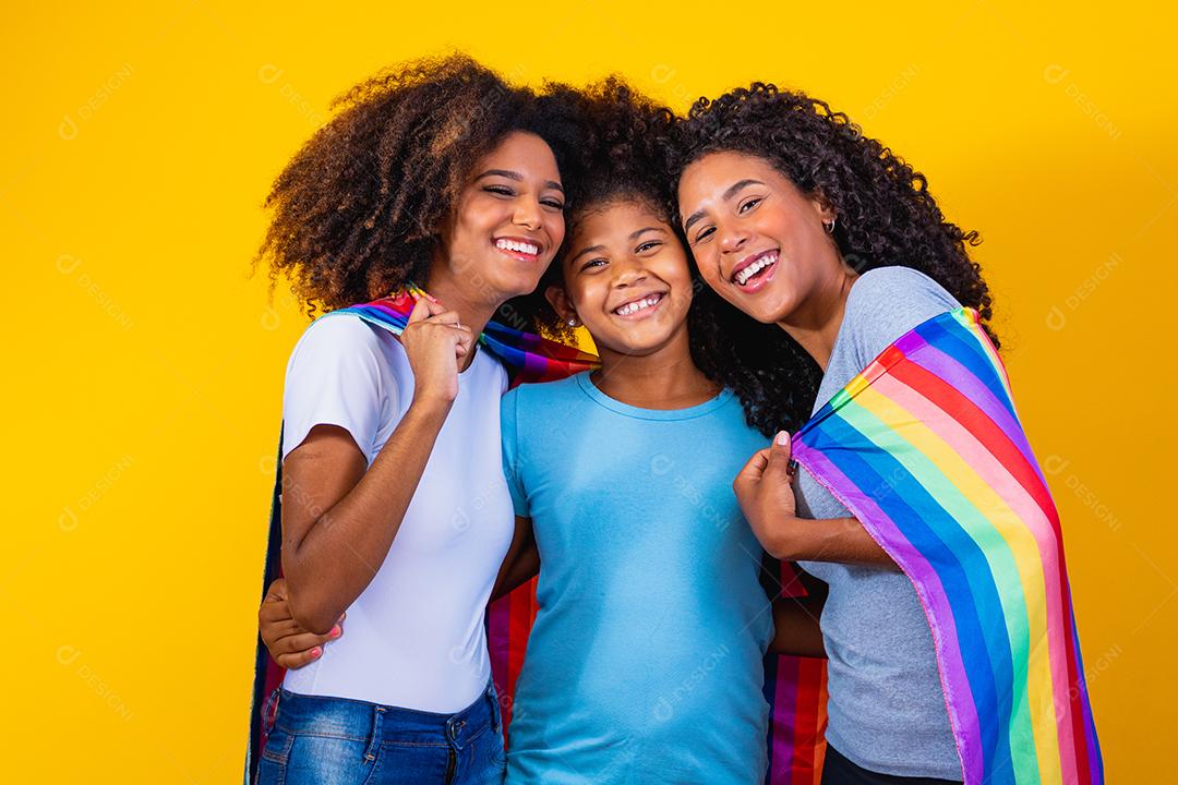 Feliz casal de lésbicas com criança em fundo amarelo. Casal junto com filha adotiva, conceito de adoção