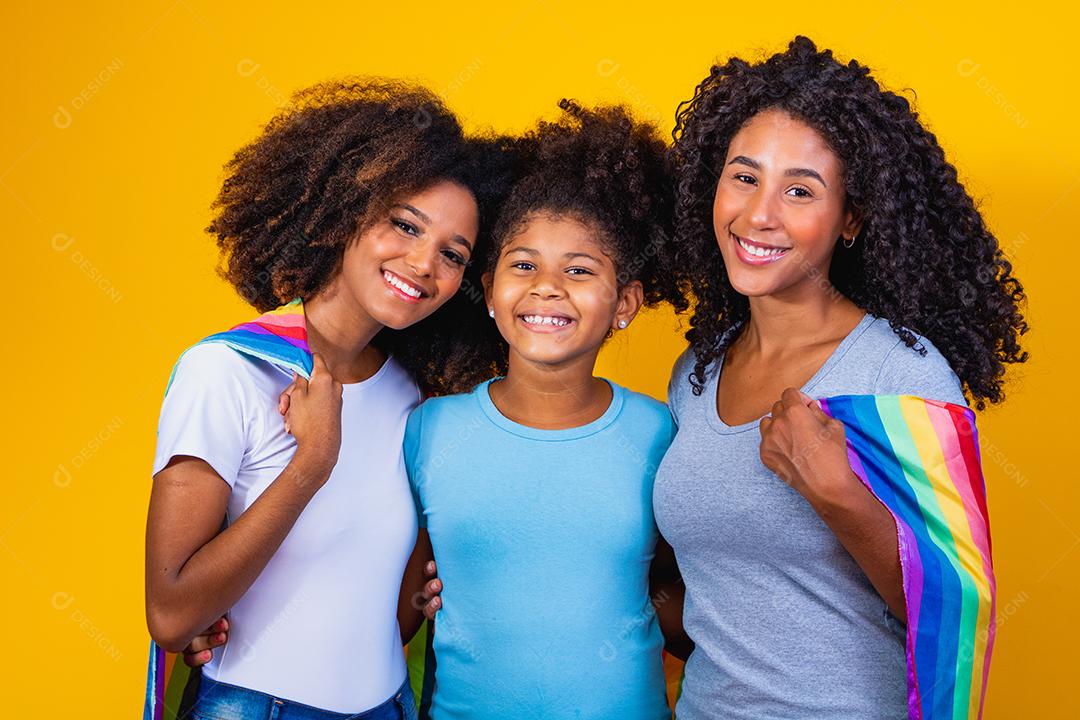 Feliz casal de lésbicas com criança em fundo amarelo. Casal junto com filha adotiva, conceito de adoção