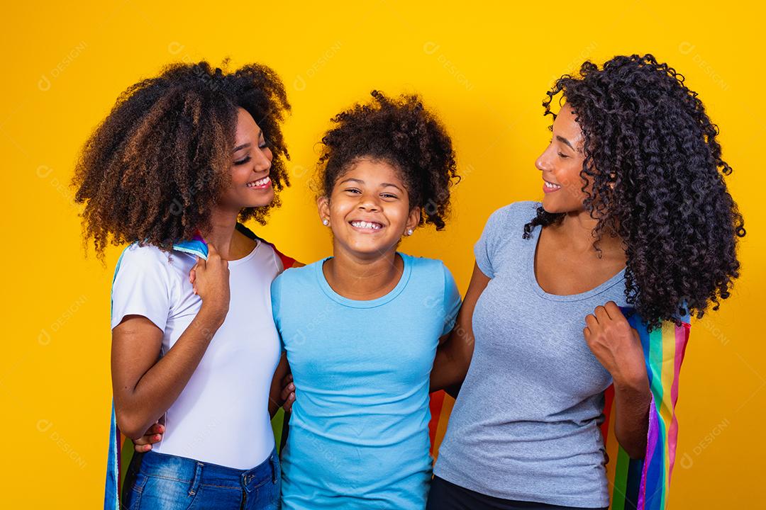 Feliz casal de lésbicas com criança em fundo amarelo. Casal junto com filha adotiva, conceito de adoção