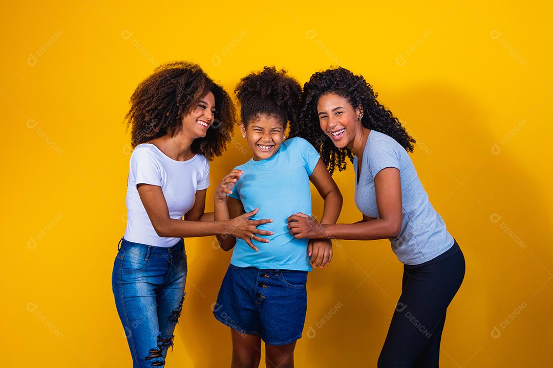 Feliz casal de lésbicas com criança em fundo amarelo. Casal junto com filha adotiva, conceito de adoção