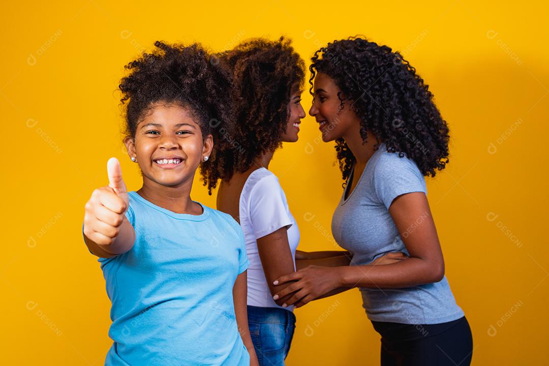 Feliz casal de lésbicas com criança em fundo amarelo. Casal junto com filha adotiva, conceito de adoção