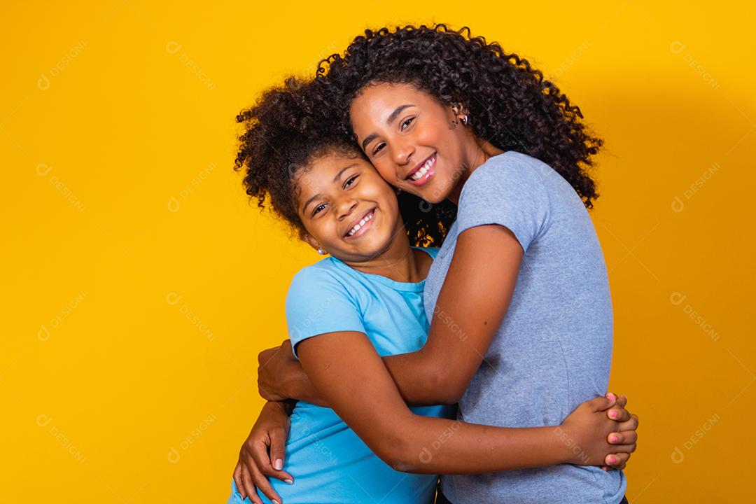 Retrato de jovem mãe e filha afro-americana em fundo amarelo. família brasileira.