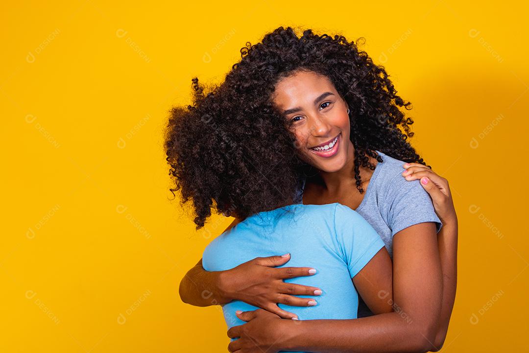 Retrato de jovem mãe e filha afro-americana em fundo amarelo. família brasileira.