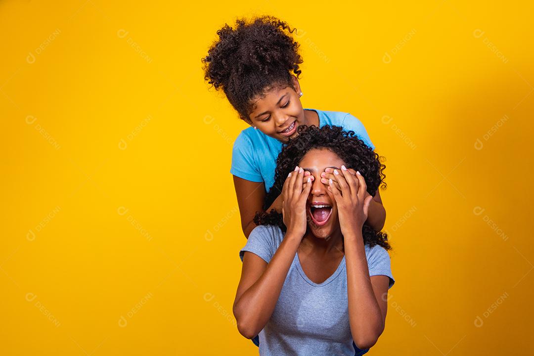 Retrato de jovem mãe e filha afro-americana em fundo amarelo. família brasileira.