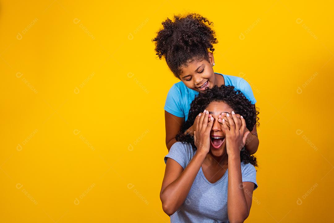 Retrato de jovem mãe e filha afro-americana em fundo amarelo. família brasileira.