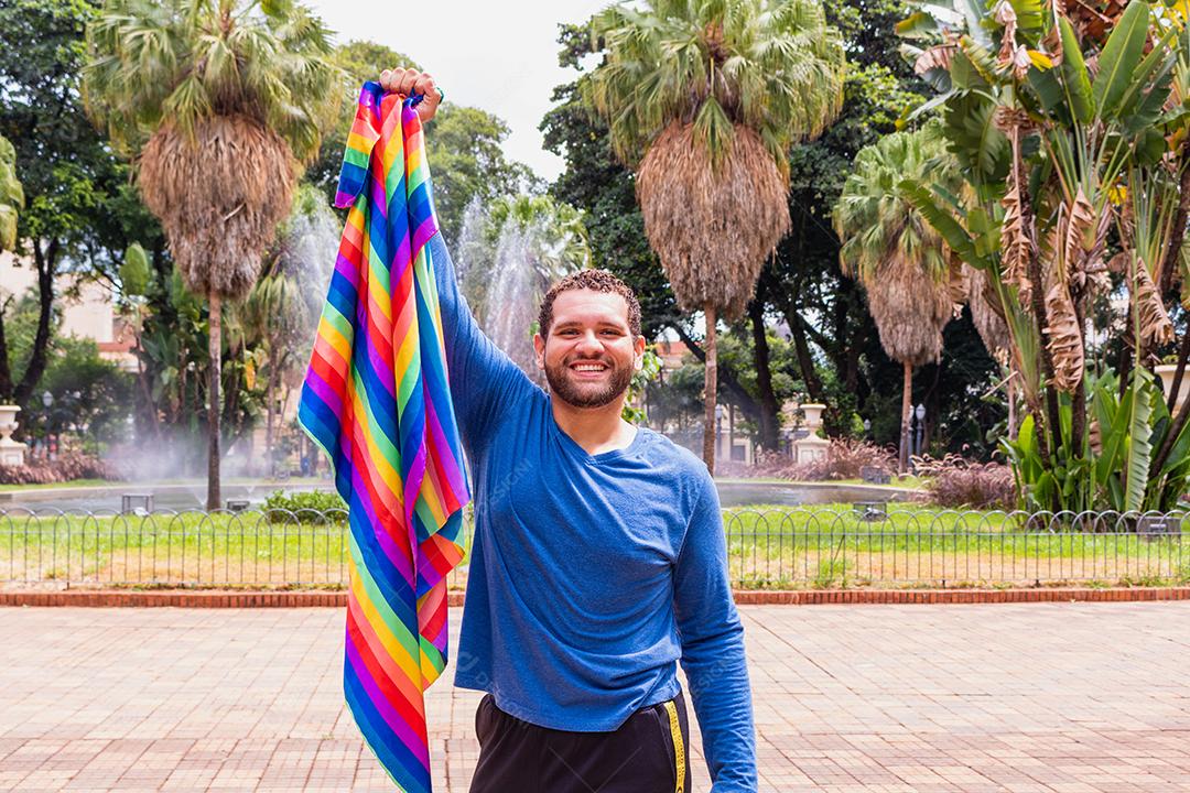 Jovem bonito com movimento do orgulho LGBT da bandeira do arco-íris na mão. orgulho gay