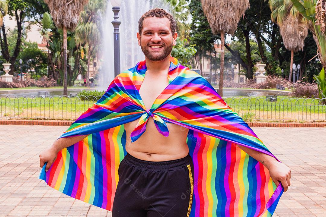 Jovem bonito com movimento do orgulho LGBT da bandeira do arco-íris na mão