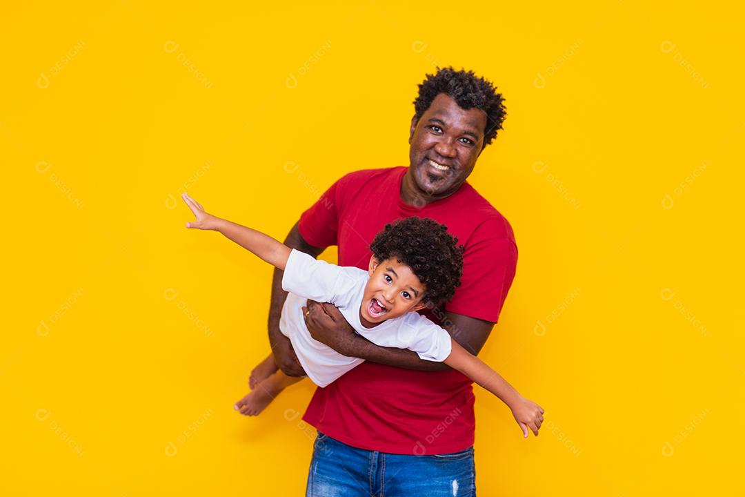 Pai e filho afro em fundo amarelo, sorrindo e brincando. Conceito de dia dos pais