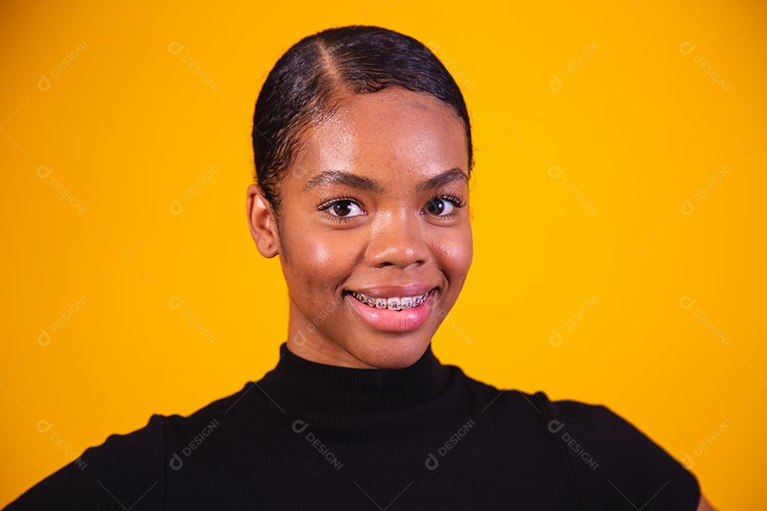 Mulher afro sorrindo sobre fundo amarelo.