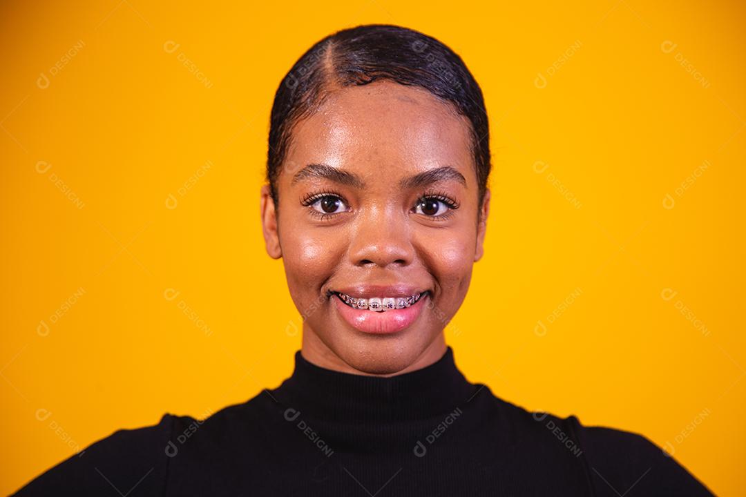 Mulher afro sorrindo sobre fundo amarelo.