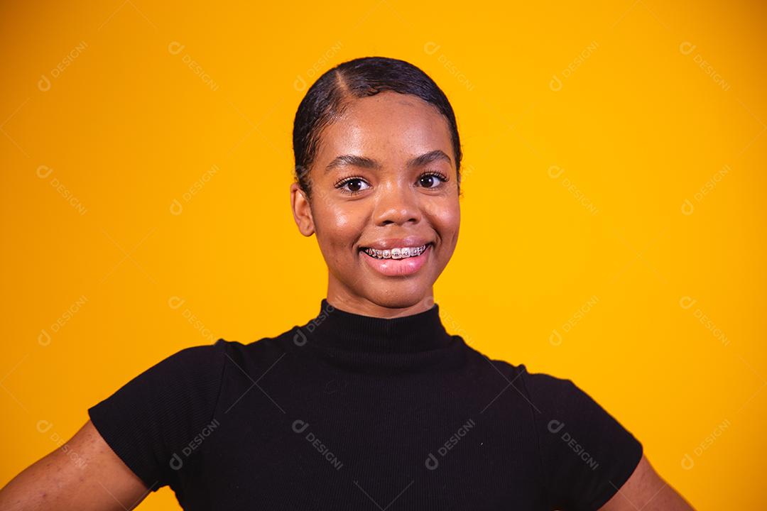 Mulher afro sorrindo sobre fundo amarelo.