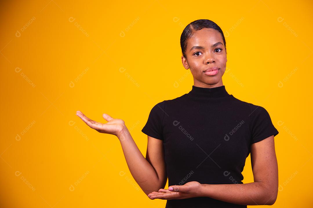 Jovem linda mulher afro feliz apontando para o lado, indicando