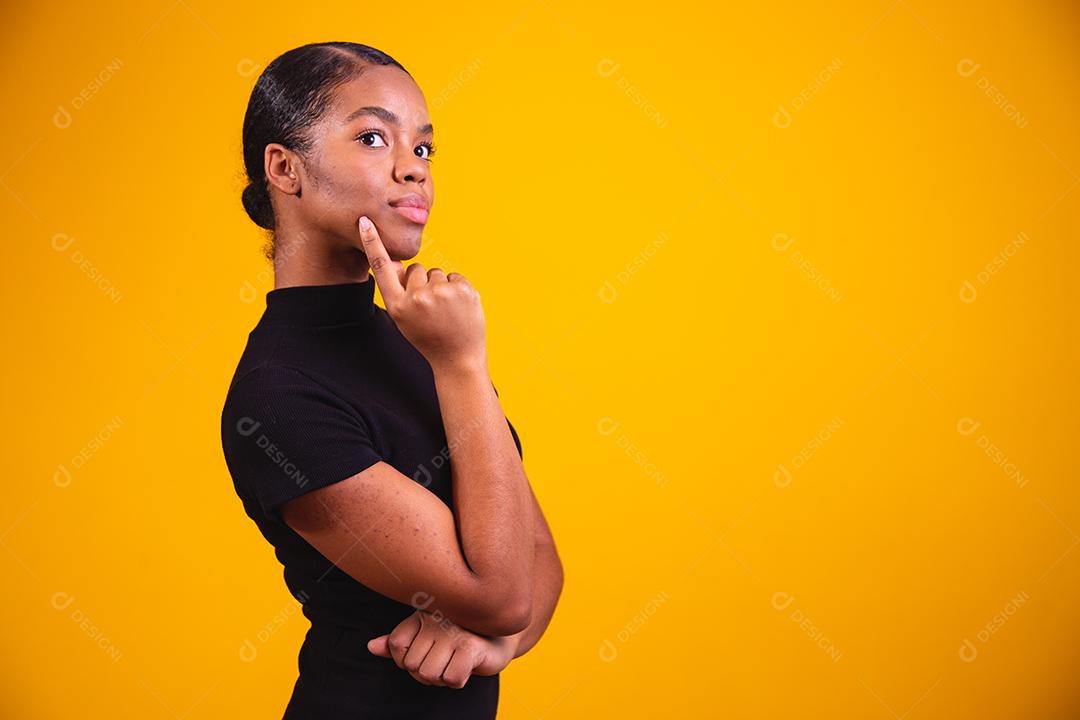 mulher pensando em fundo amarelo. Mulher confusa e pensativa