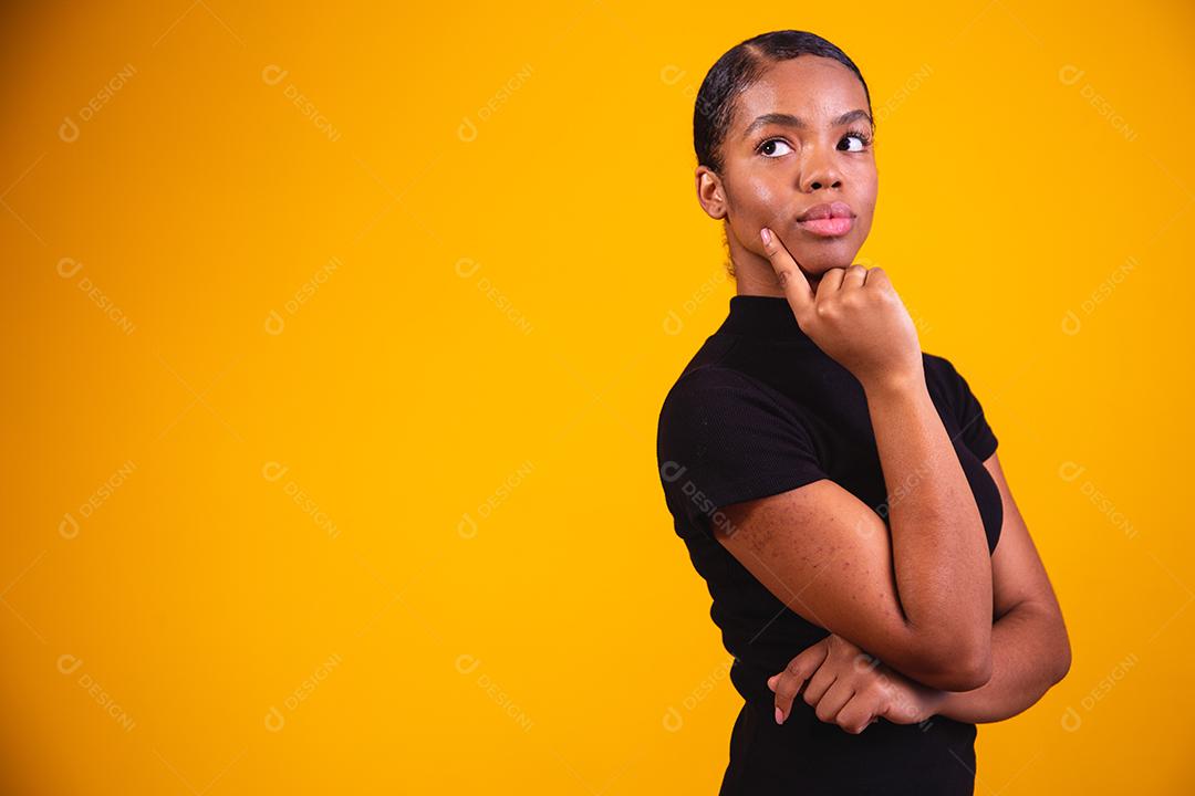 mulher pensando em fundo amarelo. Mulher confusa e pensativa