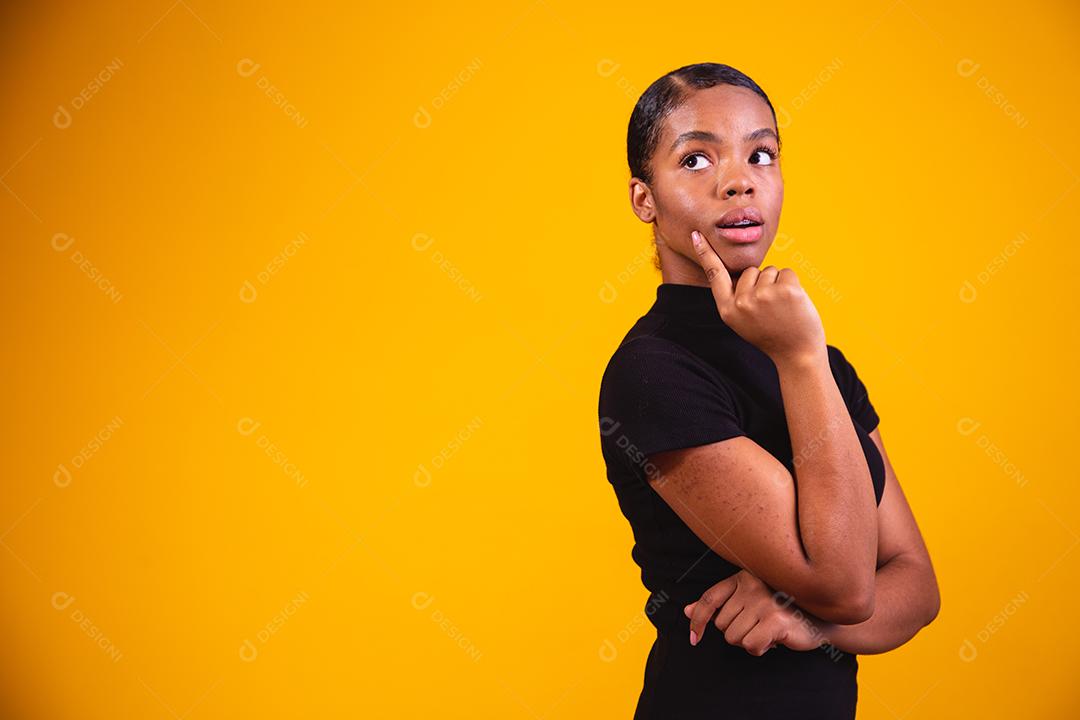mulher pensando em fundo amarelo. Mulher confusa e pensativa