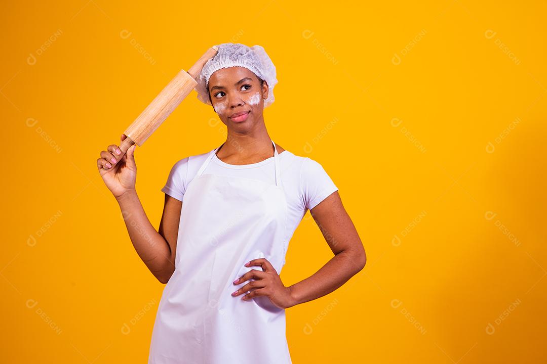 Fabricante de pizza jovem em fundo amarelo, segurando o rolo.